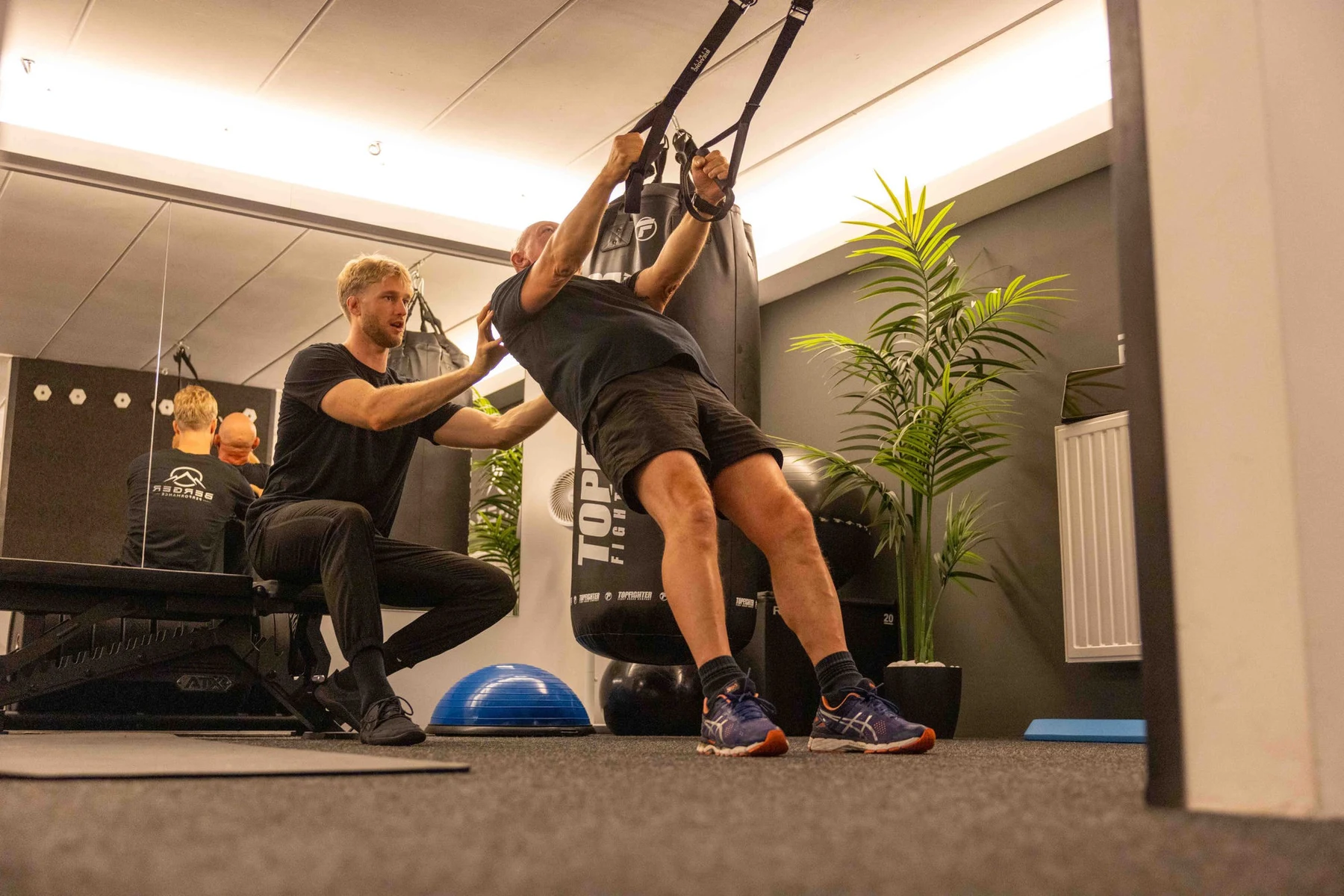 Robbe Berger begeleidt een klant tijdens een intensieve TRX-oefening in de studio